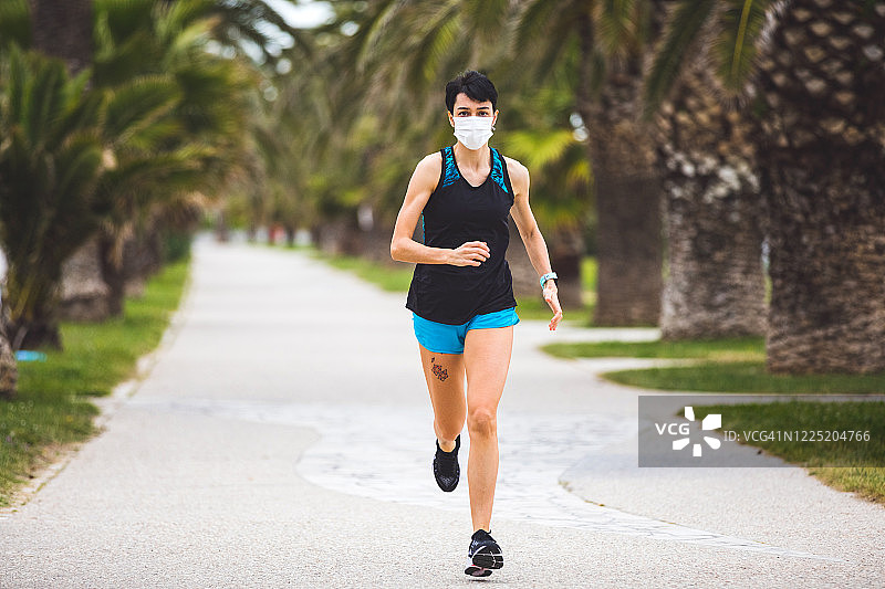 女人户外训练，戴口罩保持社交距离图片素材