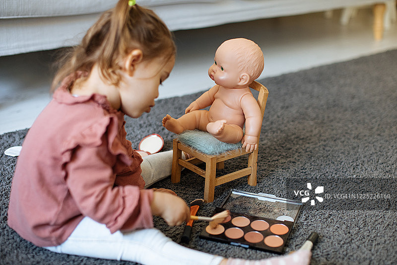 小女孩给她的玩偶化妆图片素材