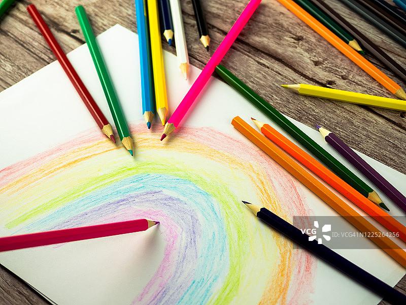 在木桌上用彩铅在纸上画彩虹图片素材