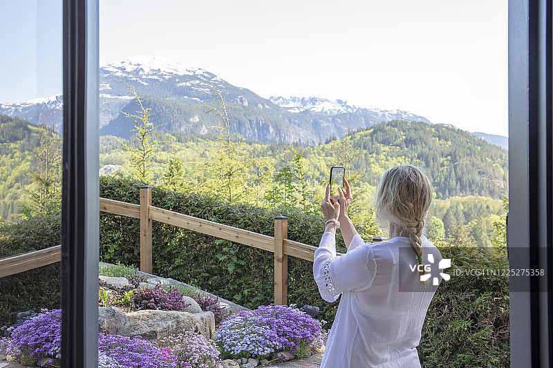 女人在家中花园用智能手机拍照图片素材