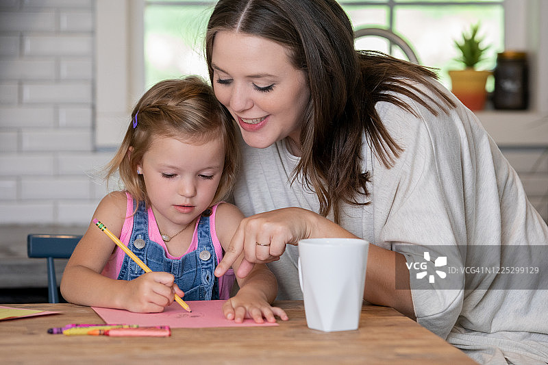 快乐的妈妈和女儿在厨房一起完成家庭作业图片素材