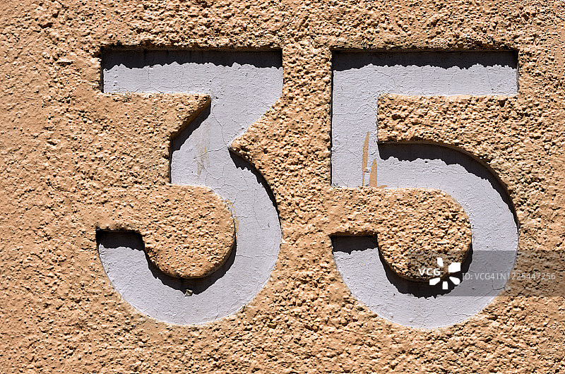 混凝土粉刷外墙上的35号浮雕（粉橙色/杏色）图片素材