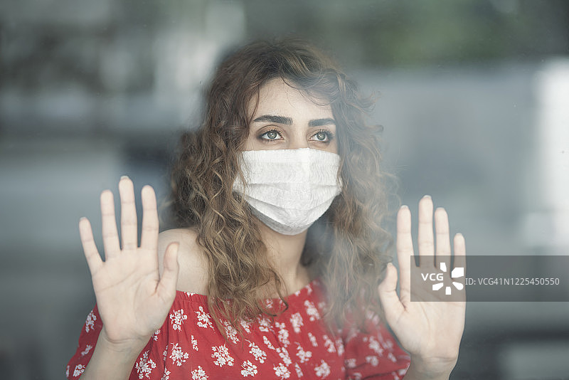 戴着医用口罩的女人向窗外看图片素材