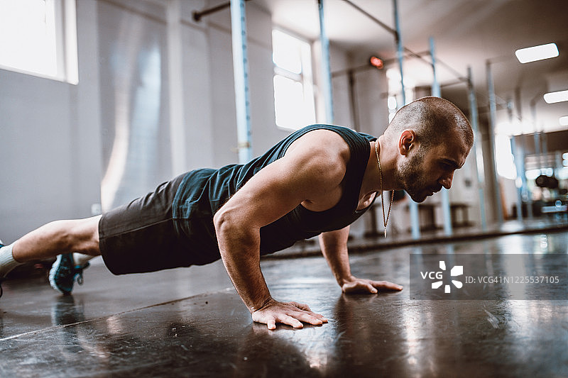在健身房里展示完美俯卧撑姿势的男性运动员图片素材