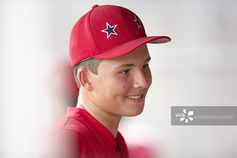 戴红色帽子和制服的青少年棒球运动员的特写肖像图片素材