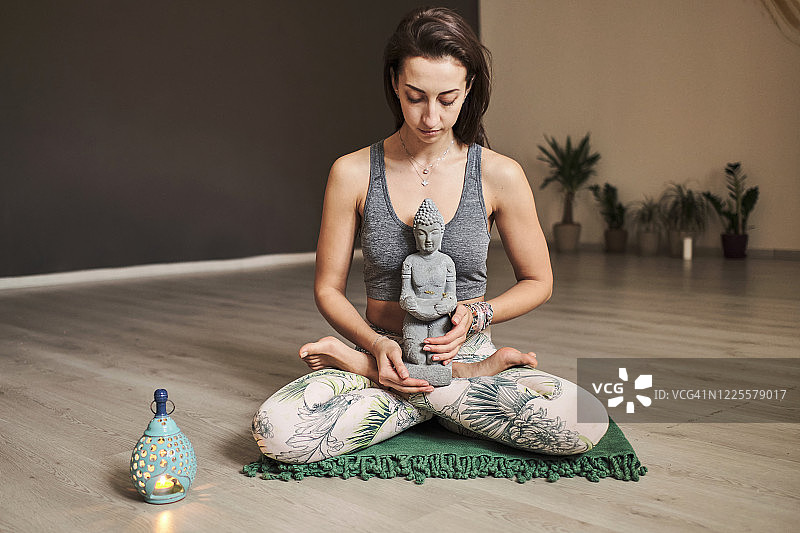 年轻女子在瑜伽馆独自冥想，有香薰灯和佛像图片素材