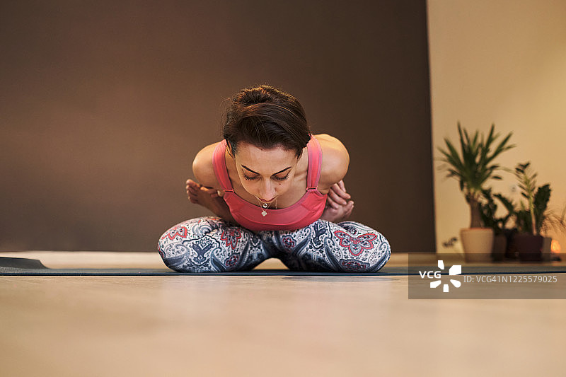 年轻女子在大气瑜伽馆的瑜伽垫上做瑜伽图片素材