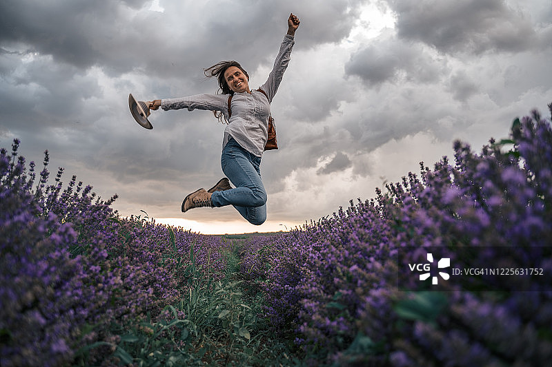 拥抱自然，在薰衣草田中跳跃的年轻女游客图片素材