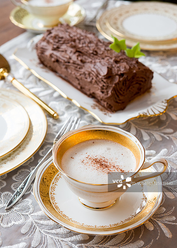 圣诞柴蛋糕前，古董骨瓷杯中的泡沫咖啡图片素材