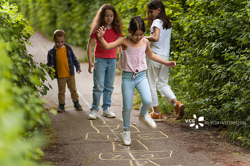 孩子们在公园里玩跳房子，用粉笔画的图片素材