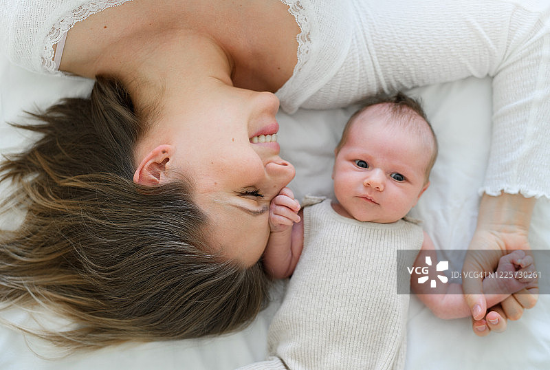 新生婴儿和母亲躺在床上的俯视图图片素材