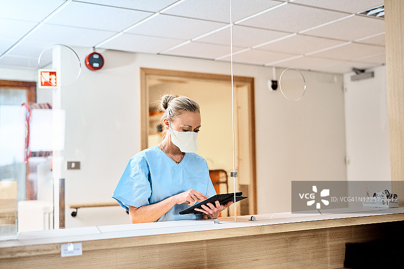 护士戴着N95口罩在医院用平板电脑工作图片素材