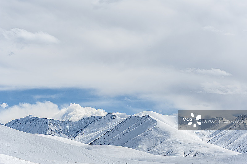 中国藏族聚居区蓝天白云下的雪山和沙漠图片素材