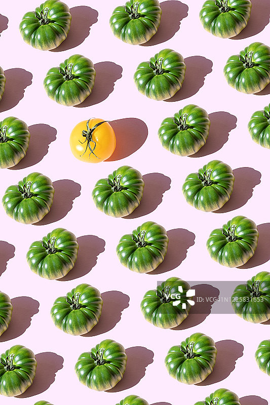 粉色背景上重复的黄色和绿色番茄图片素材