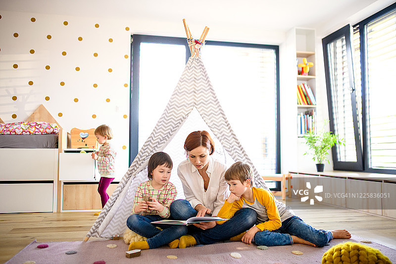 母亲在家卧室里给三个孩子读书图片素材