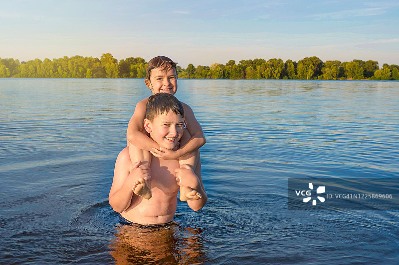 阳光明媚的日子里，孩子们在水中玩耍，看着镜头，快乐的童年图片素材