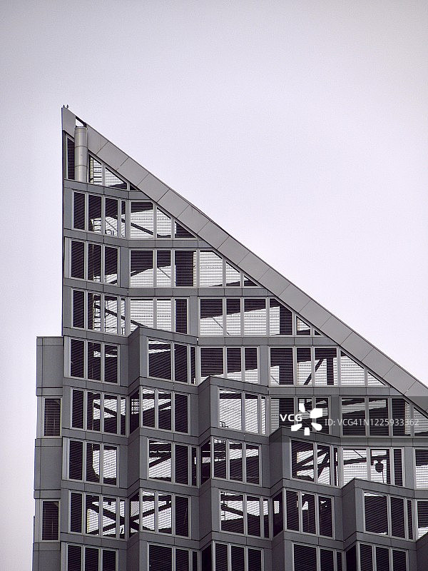 浅色天空下的现代金属玻璃摩天大楼特写图片素材