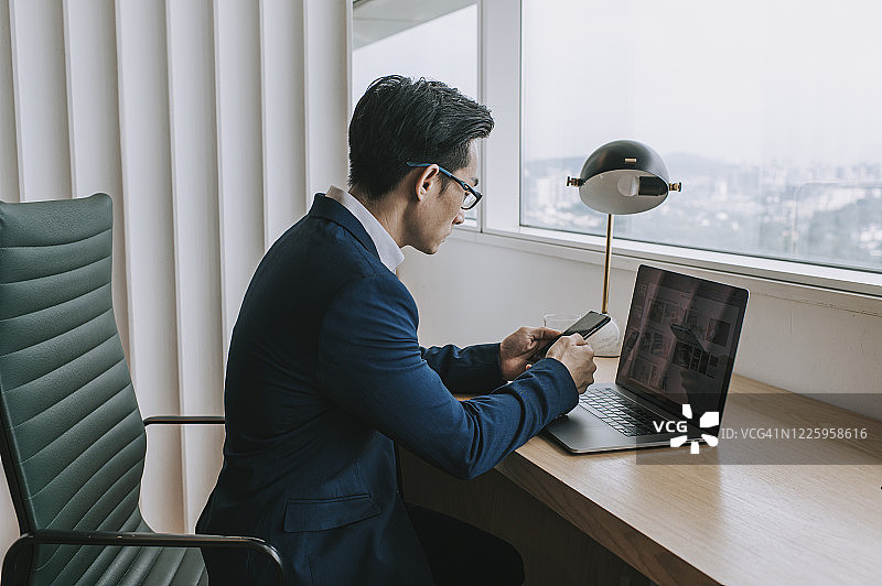 一位中国中年英俊白领在办公室工作，查看手机上的信息图片素材