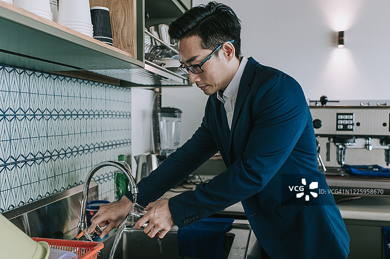 办公室里，白领经理在茶水间清洗自己的水杯图片素材