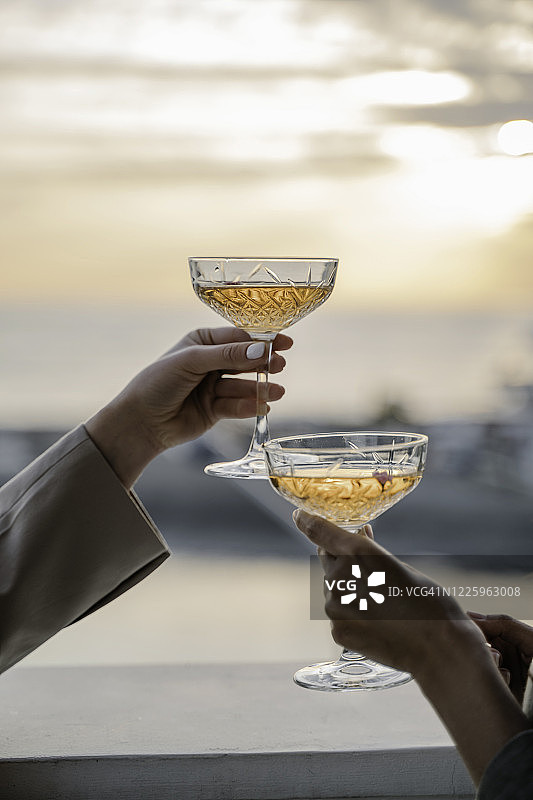 女性手持玫瑰红酒杯与日落海景图片素材