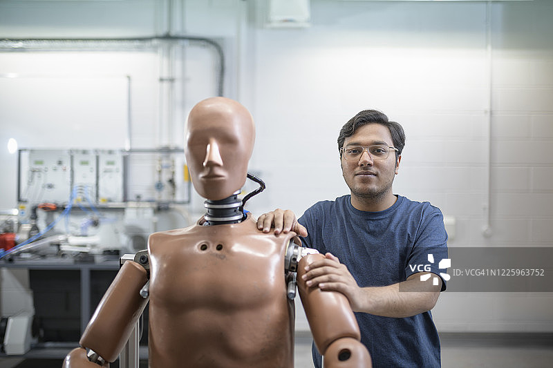 车间里站在测试人体模型后面的男学生图片素材