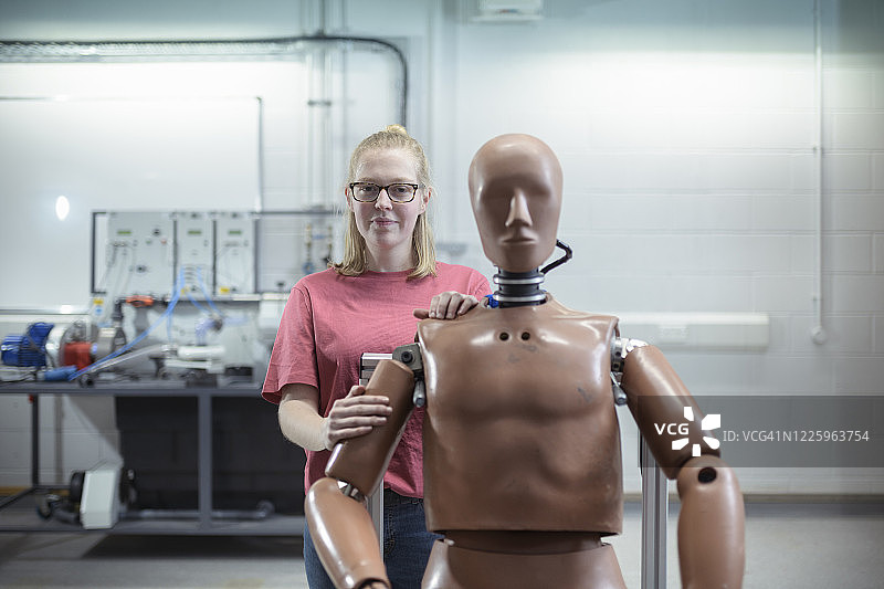 一名女学生站在车间的测试模型后面图片素材