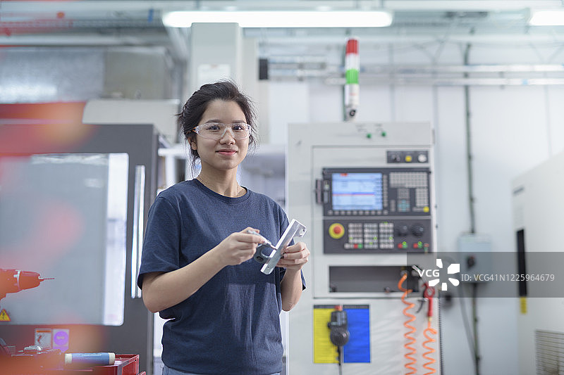 女工程师在工厂数控车床旁看向镜头图片素材