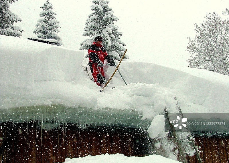 男人在屋顶上铲雪图片素材