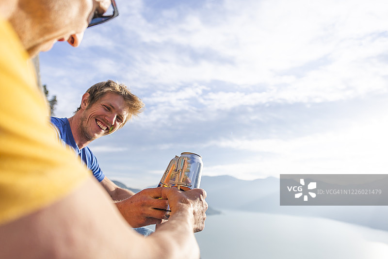 两人在酋长峰顶的日落时分欢呼并喝啤酒图片素材