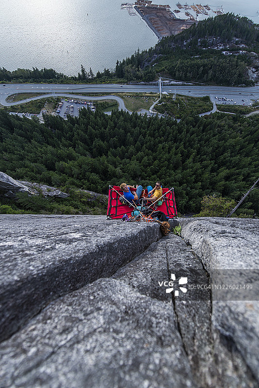 两名男子坐在悬挂帐篷里看日落的俯视图图片素材