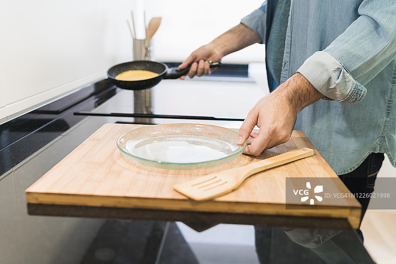 男人穿着牛仔衬衫在厨房做饭图片素材