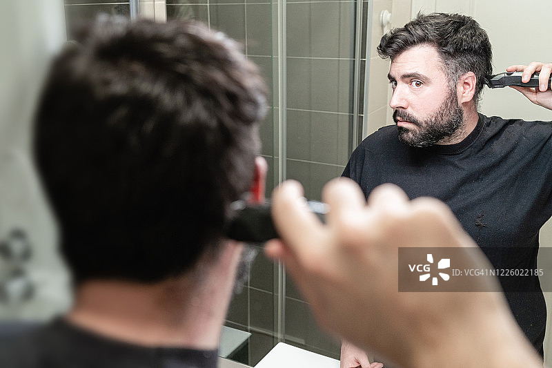 在浴室用理发器给自己理发的男人图片素材
