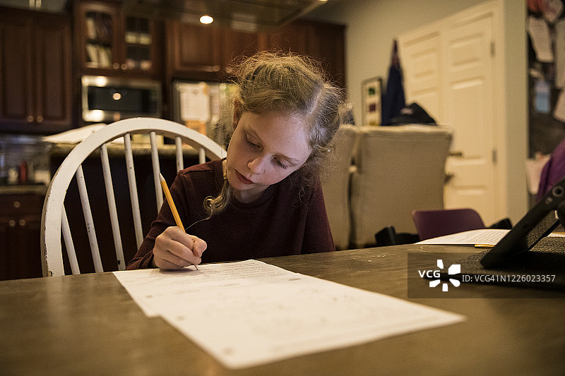 在家做功课的可爱金发女孩，梳着法式辫子图片素材