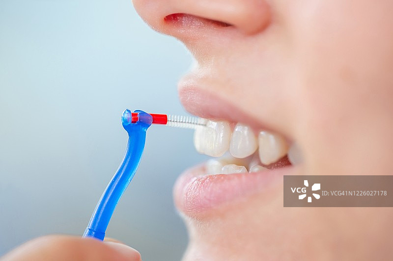 年轻女子使用齿间刷清洁牙齿的特写照片图片素材