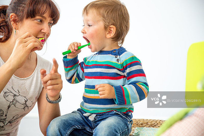 充满爱意的母亲示范如何正确地给小男孩刷牙 - 摄影素材图片素材