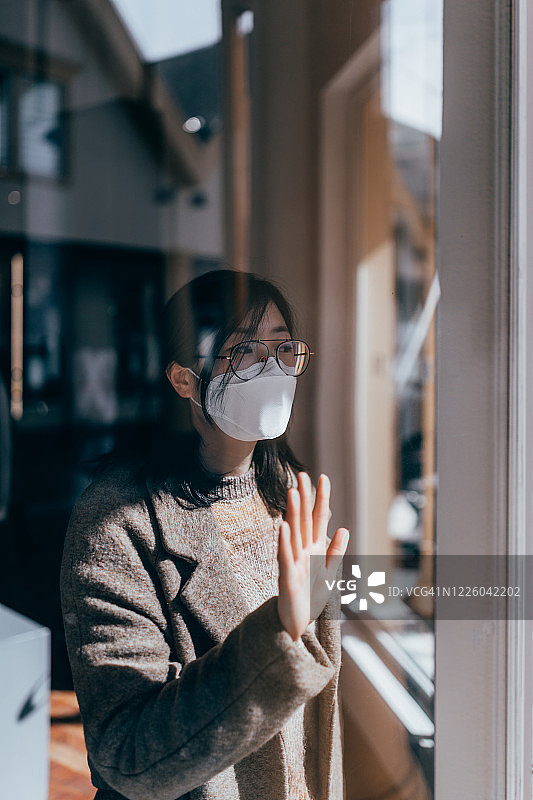戴着面具的窗后女人图片素材