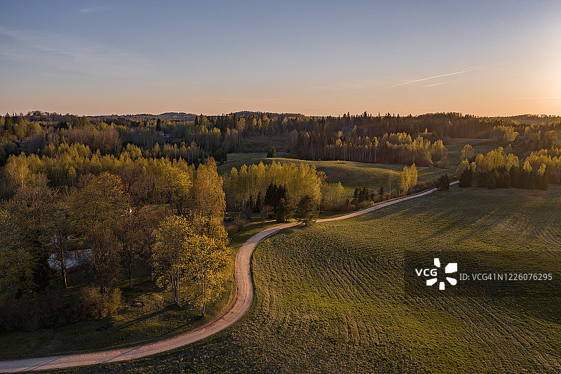 日落时分蜿蜒的道路、田野和森林航拍图片素材