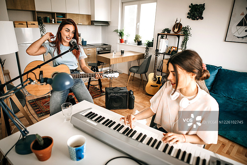 两位年轻女音乐人在家庭音乐工作室创作。图片素材