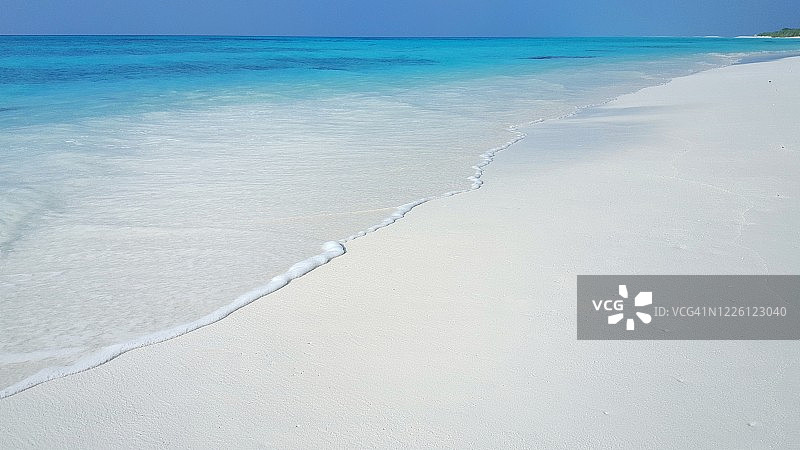 巴哈马蓝天下延伸至海洋的白色沙滩图片素材