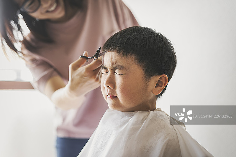 母亲在家给儿子剪头发图片素材