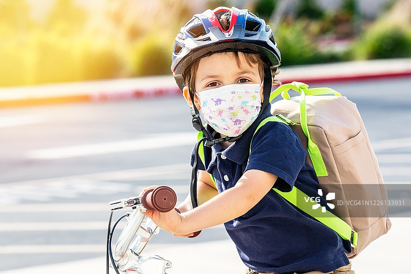 小男孩戴着防护面罩和背包骑自行车图片素材