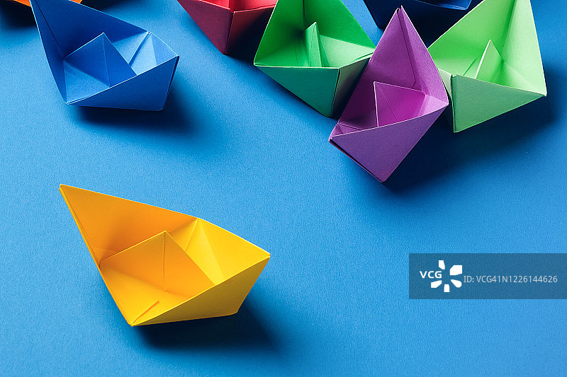 明亮蓝色背景上的彩色纸船，留白区域图片素材
