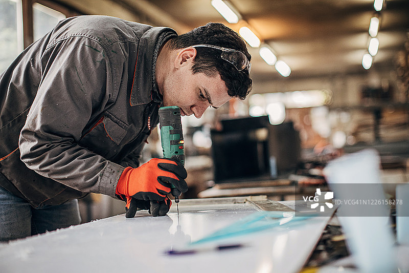 一个男人在车间用钻头工作图片素材