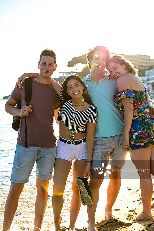 在海滩上拥抱并为相机摆姿势的年轻朋友们图片素材