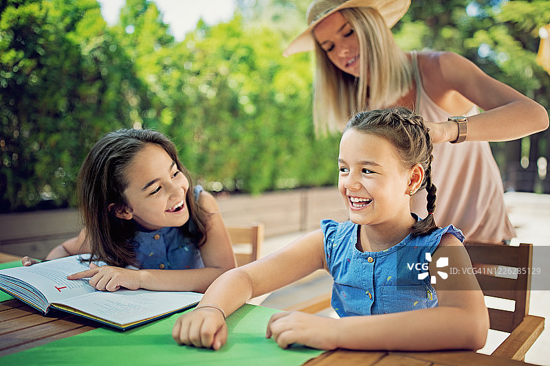 母亲在露台上给女儿编辫子图片素材