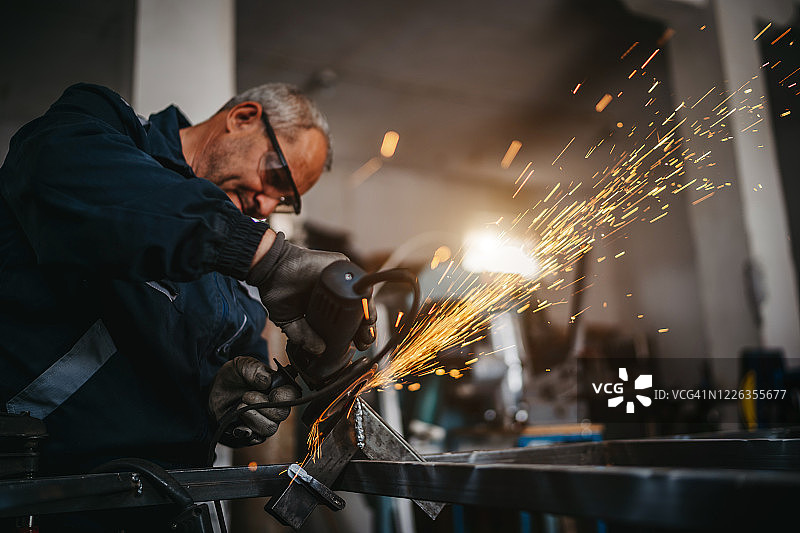 在车间使用电动研磨机的年长男人图片素材