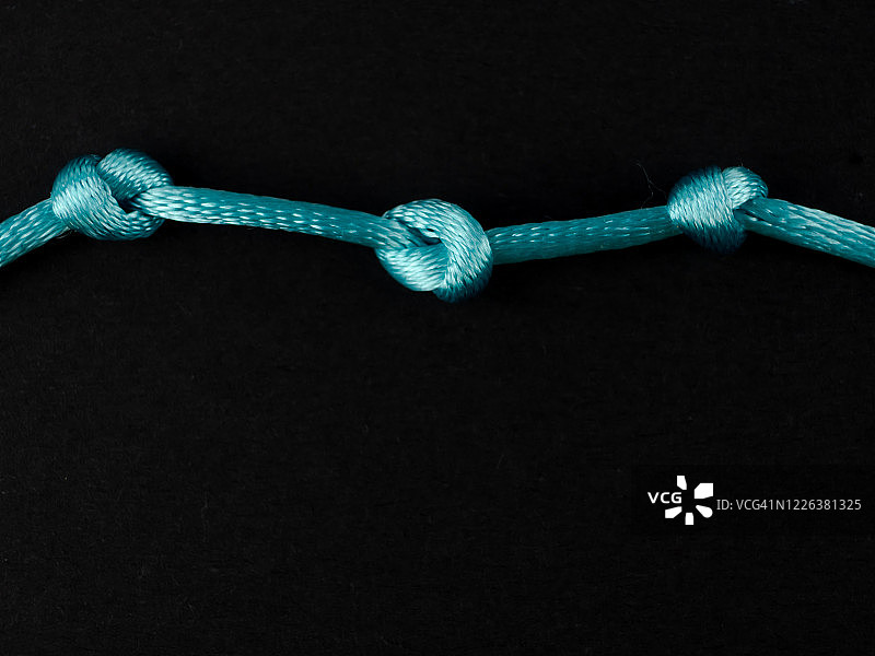 黑色背景上的蓝色细绳结图片素材