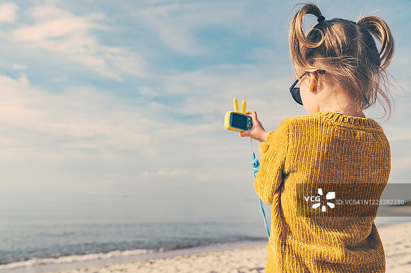 扎着滑稽马尾辫的小女孩在拍摄大海图片素材