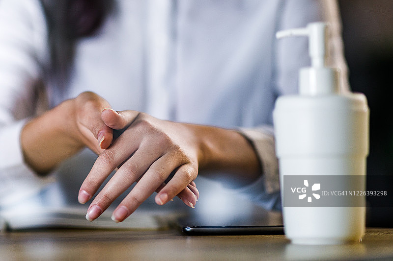 女人用外用酒精消毒双手的特写图片素材