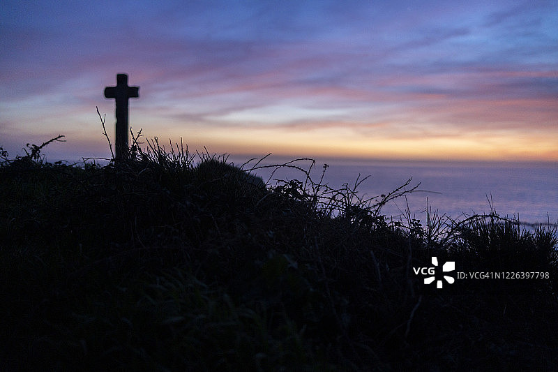 岩石顶端带有海景的古老十字架轮廓图片素材